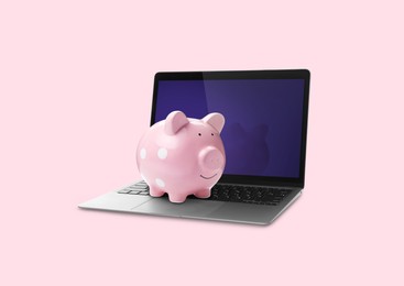 Piggy bank and laptop on pink background. Online banking