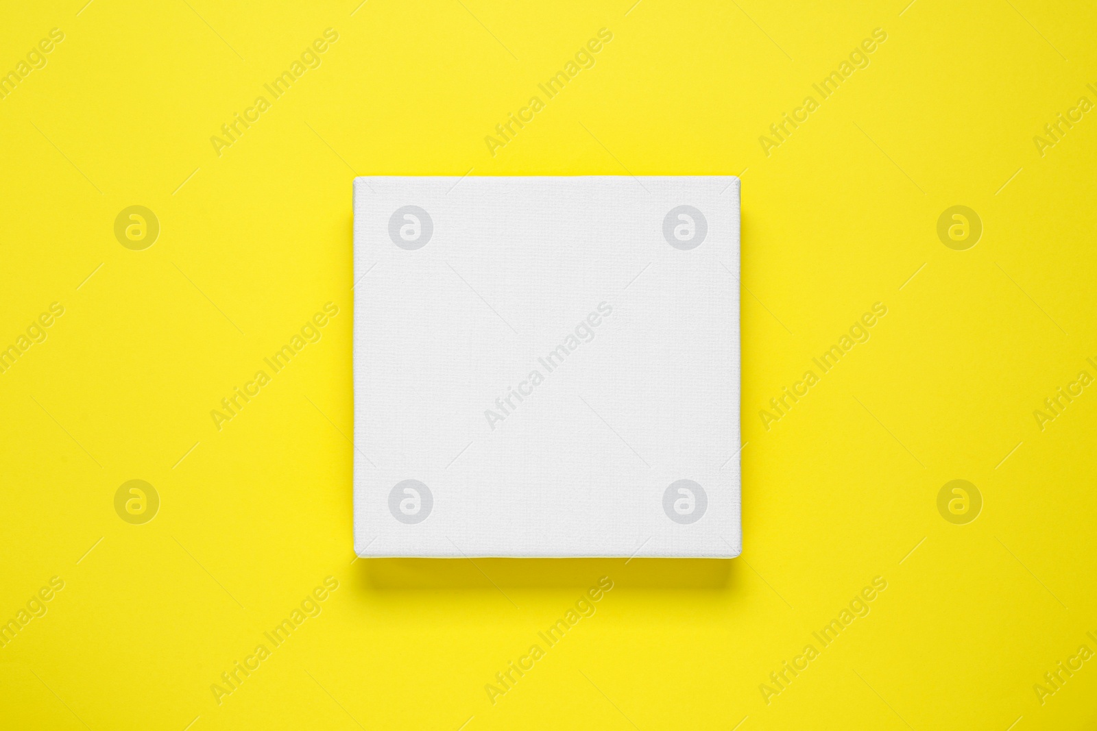 Photo of Blank canvas on yellow background, top view. Space for design