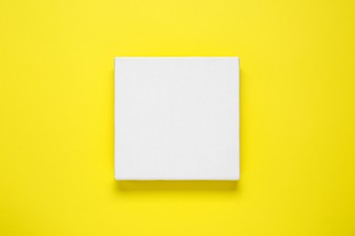 Photo of Blank canvas on yellow background, top view. Space for design