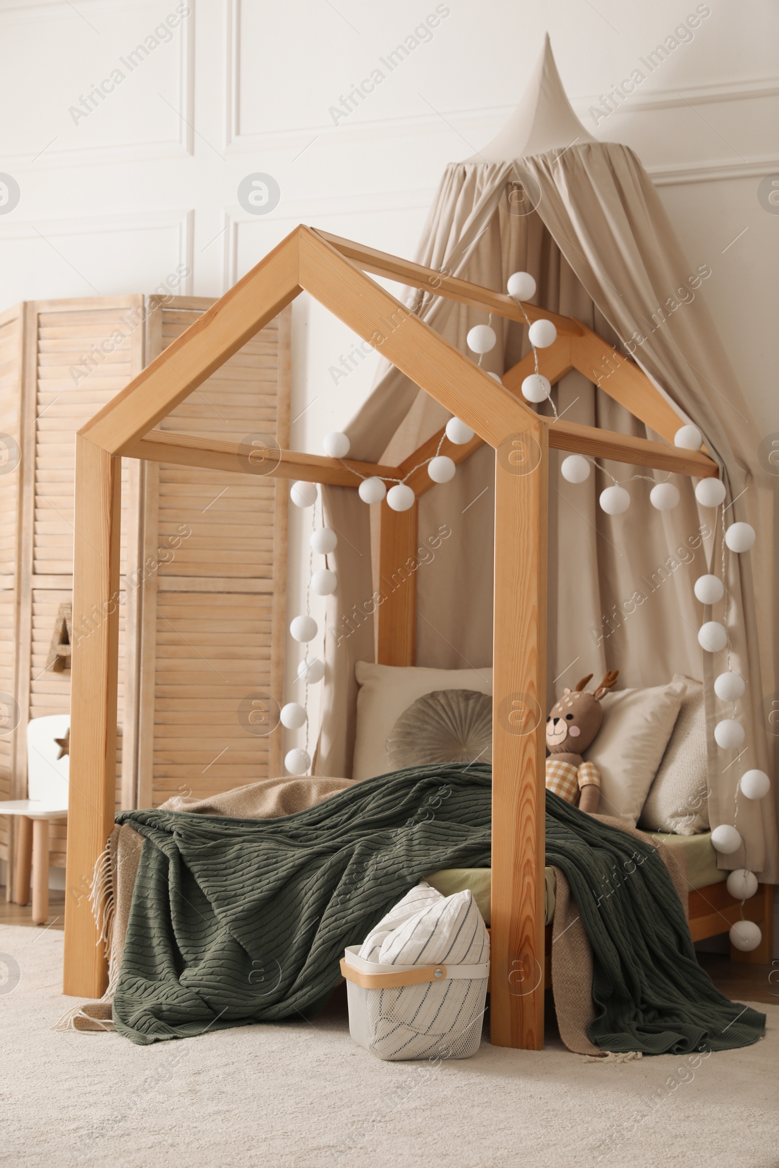 Photo of Stylish child room interior with wooden house bed