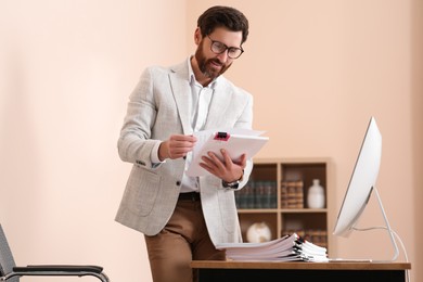 Photo of Happy businessman working with documents in modern office