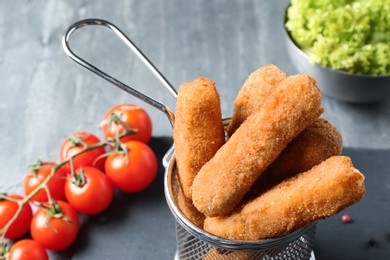 Photo of Basket of tasty crispy cheese sticks on table, closeup