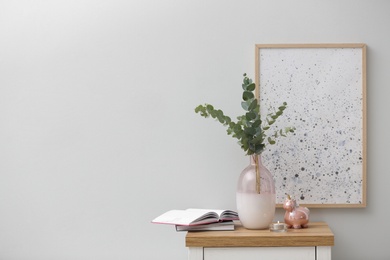 Photo of Vase with fresh eucalyptus branches on cabinet in room. Interior design