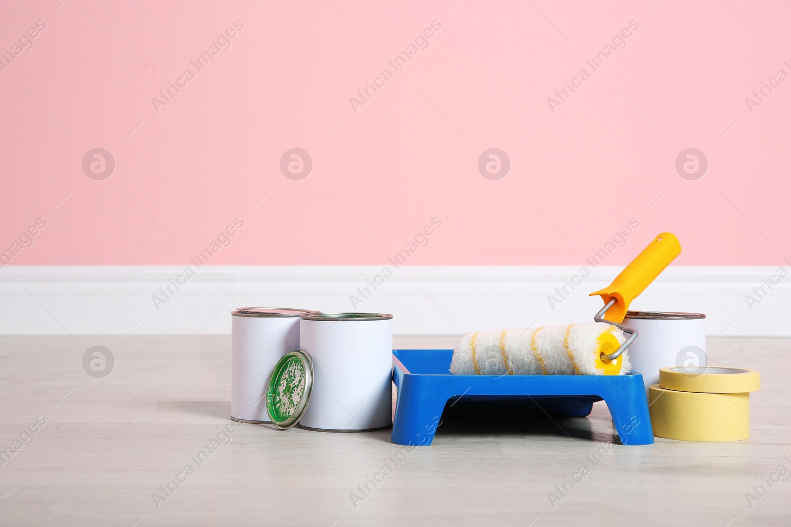 Photo of Cans of paint and decorator tools on wooden floor indoors