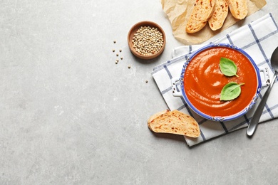 Photo of Fresh homemade tomato soup served with bread on grey table, top view. Space for text