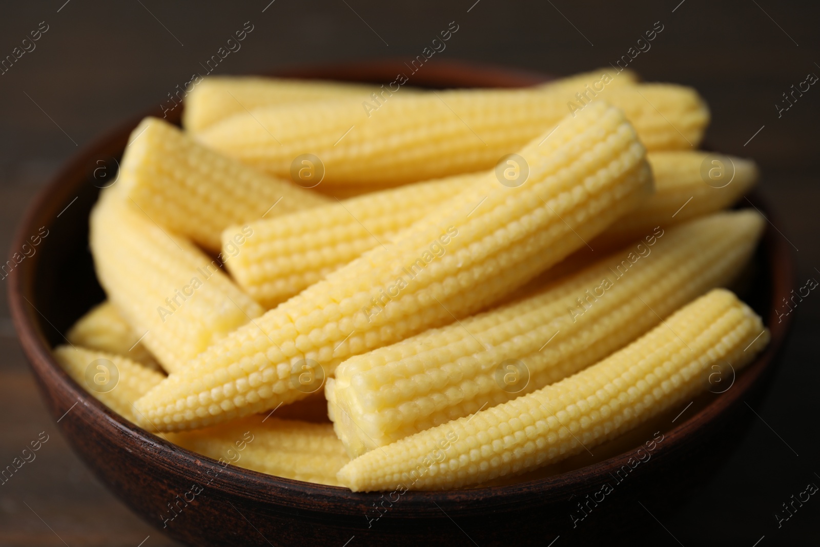 Photo of Tasty fresh yellow baby corns in bowl on table, closeup