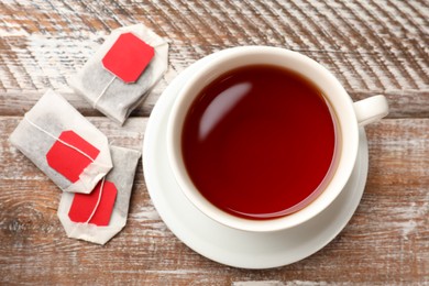 Tea bags and cup of aromatic drink on wooden rustic table, top view