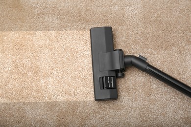 Image of Vacuuming dirty beige carpet. Clean area after using device, top view