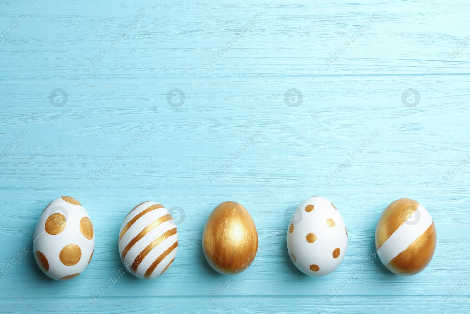 Photo of Set of traditional Easter eggs decorated with golden paint on wooden background, top view. Space for text