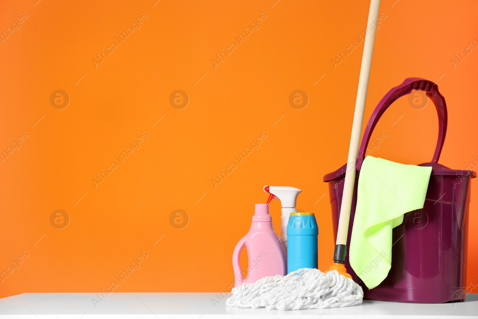 Photo of Mop bucket with cleaning supplies on color background