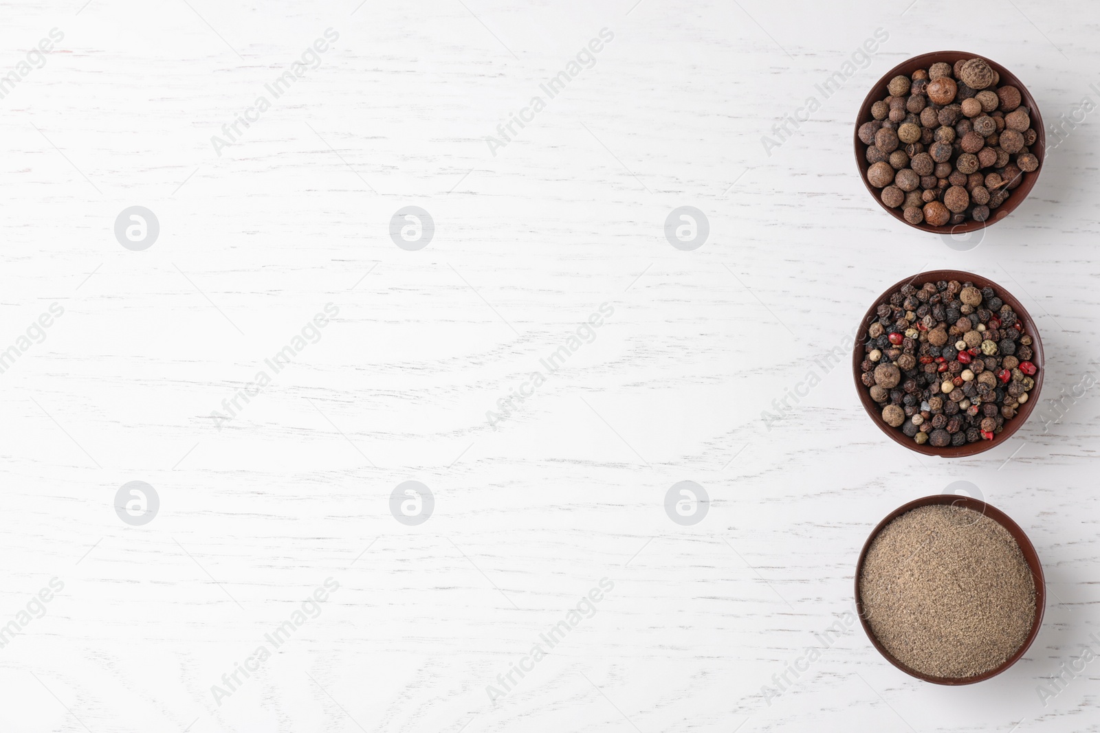 Photo of Ground pepper and corns on white wooden table, flat lay. Space for text