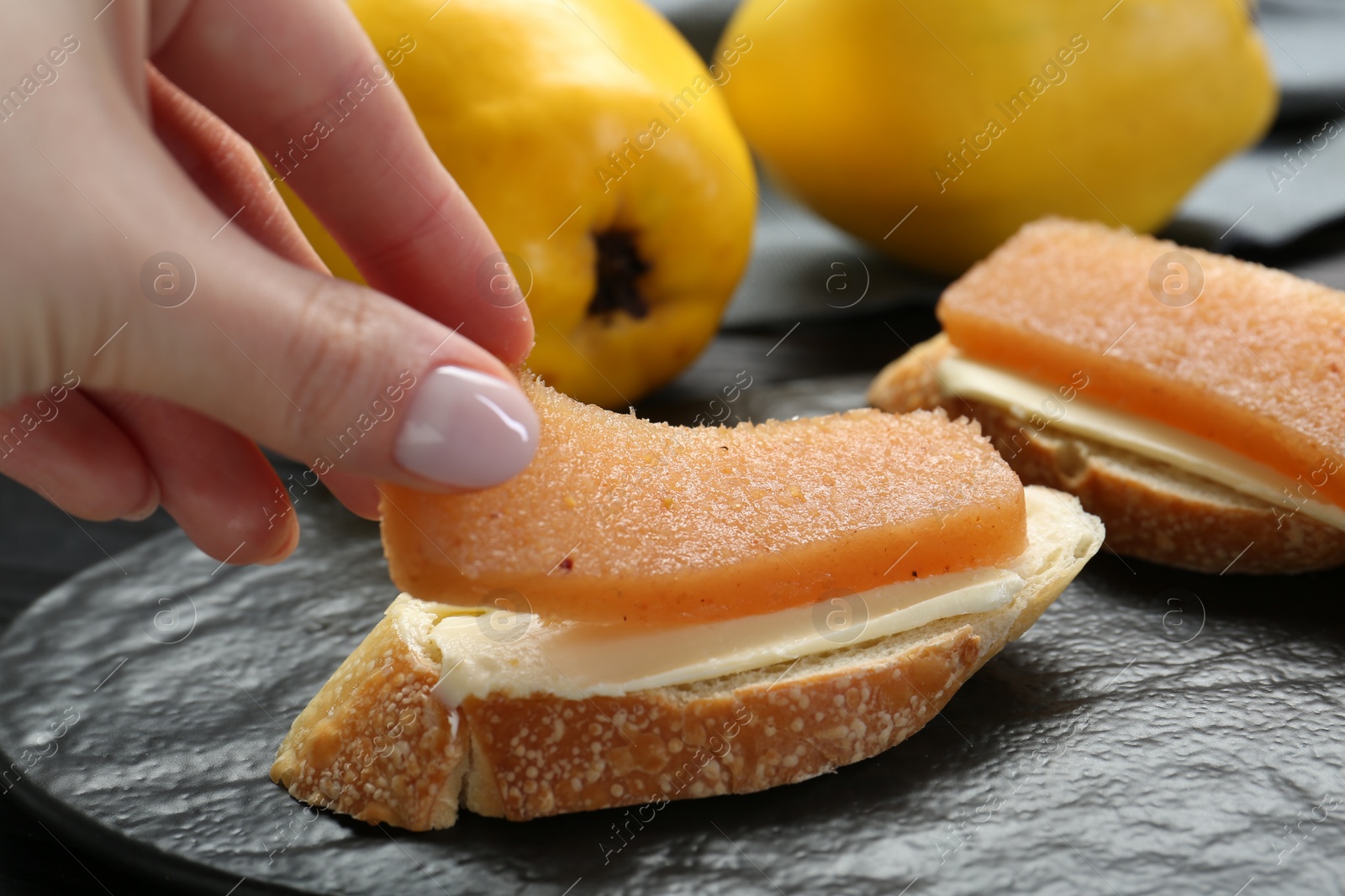 Photo of Woman making sandwich with quince paste at table, closeup