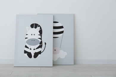 Photo of Adorable pictures of zebra and air balloon on floor near white wall. Children's room interior elements
