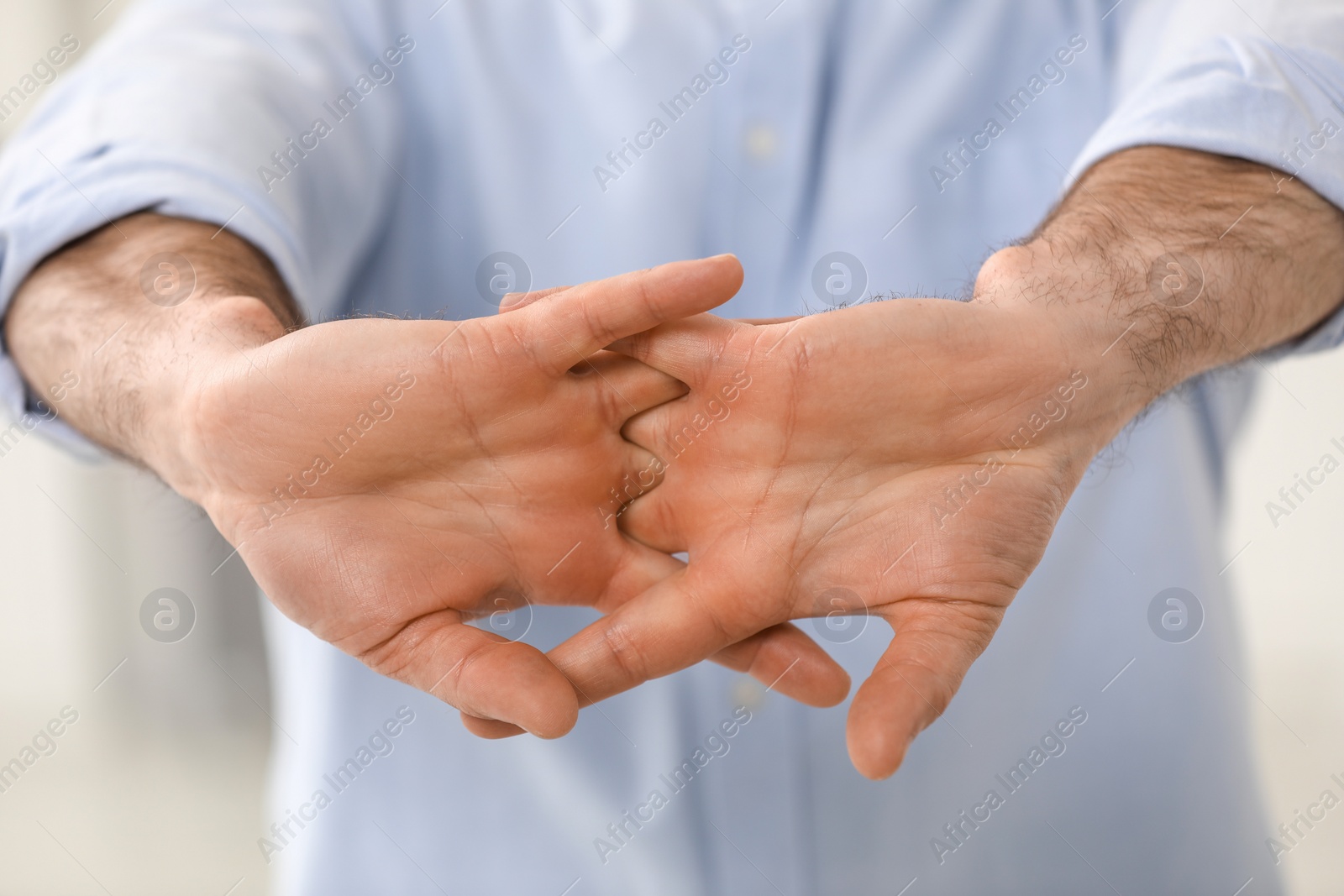 Photo of Man cracking his knuckles on blurred background, closeup. Bad habit