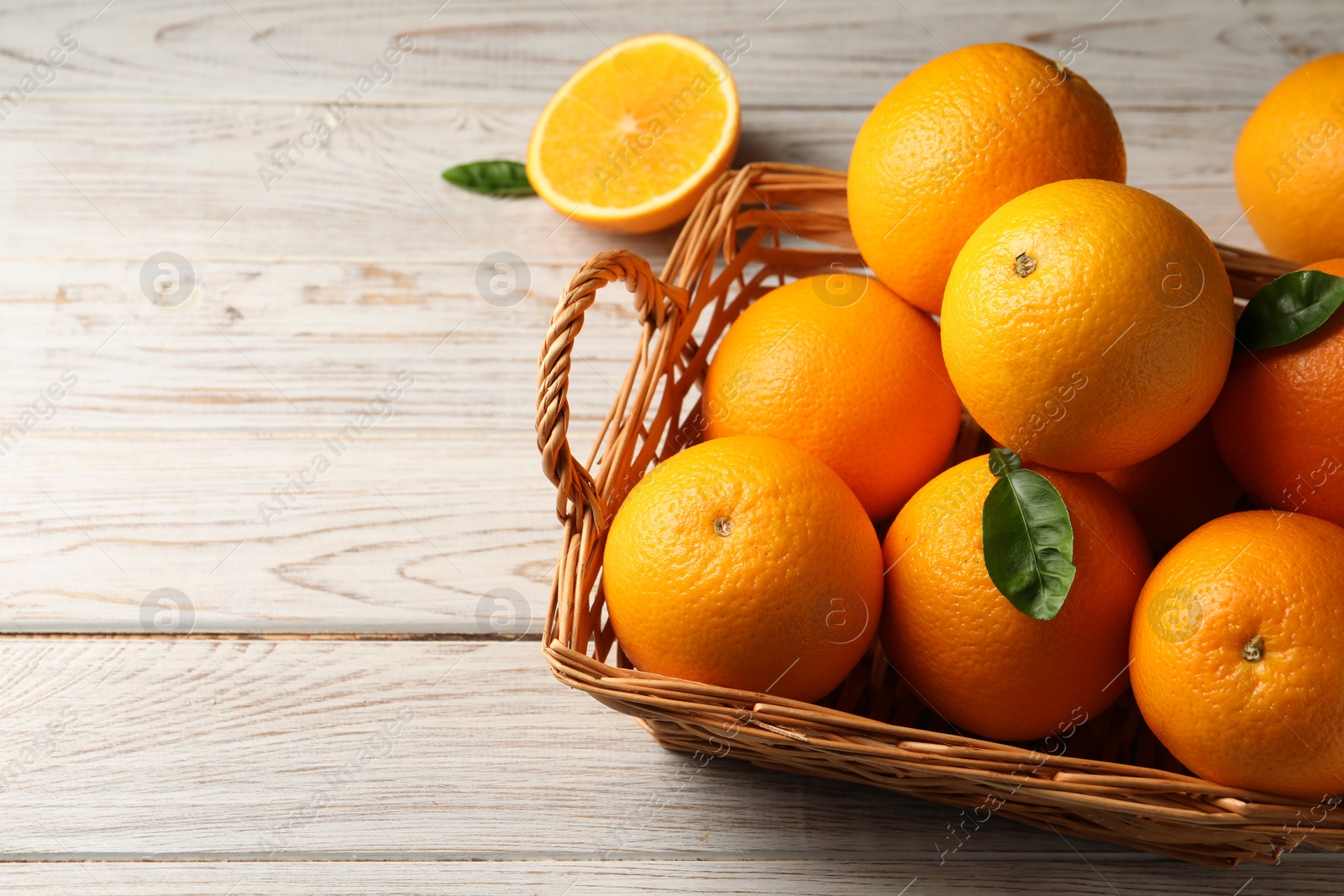 Photo of Many ripe oranges and green leaves on wooden table. Space for text