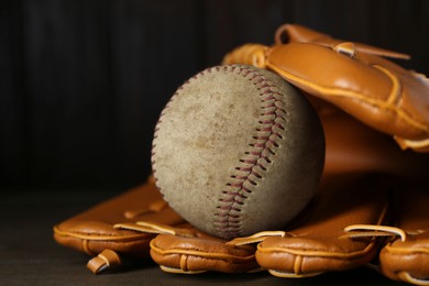 Image of Leather baseball glove with old worn ball on wooden table, closeup
