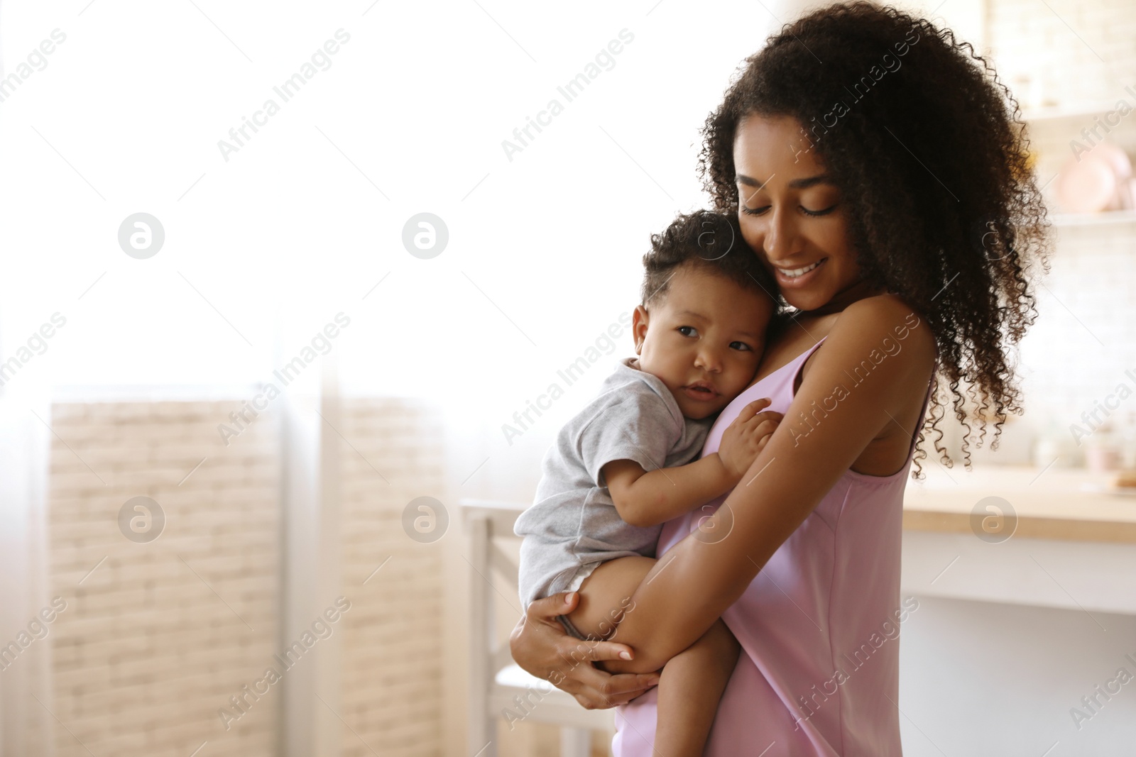 Photo of African-American woman with her baby at home. Happiness of motherhood