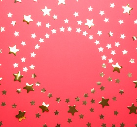 Frame made of confetti stars with space for text on red background, top view. Christmas celebration