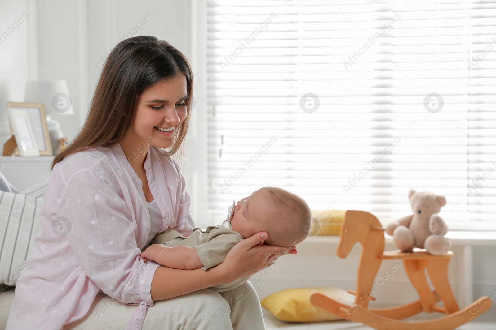 Photo of Young woman with her sleeping baby at home