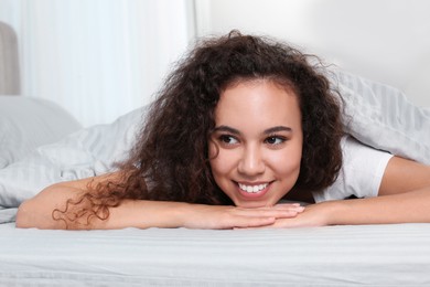 Photo of Happy beautiful African American woman lying in bed at home