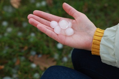 Woman holding hail grains after thunderstorm outdoors, closeup