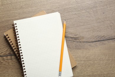 Photo of Notebooks and pencil on wooden table, top view. Space for text