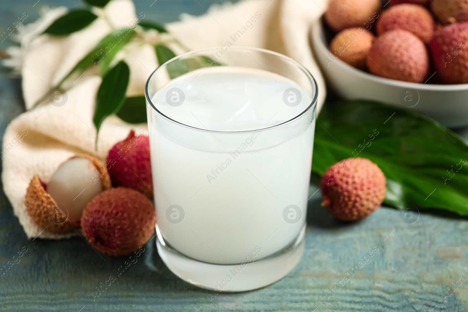 Photo of Fresh lychee juice and fruits on blue wooden table