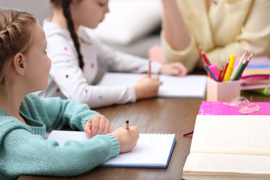 Photo of Little girls doing homework with mother at table