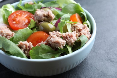 Photo of Bowl of delicious salad with canned tuna and vegetables on black table, closeup