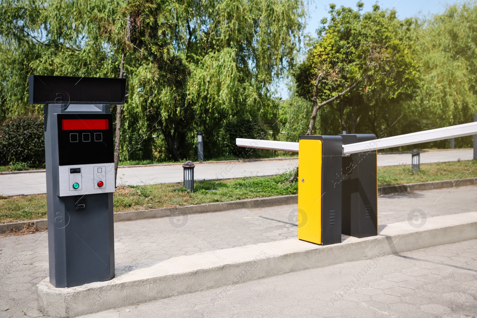 Photo of Modern road barriers and parking meter outdoors on sunny day