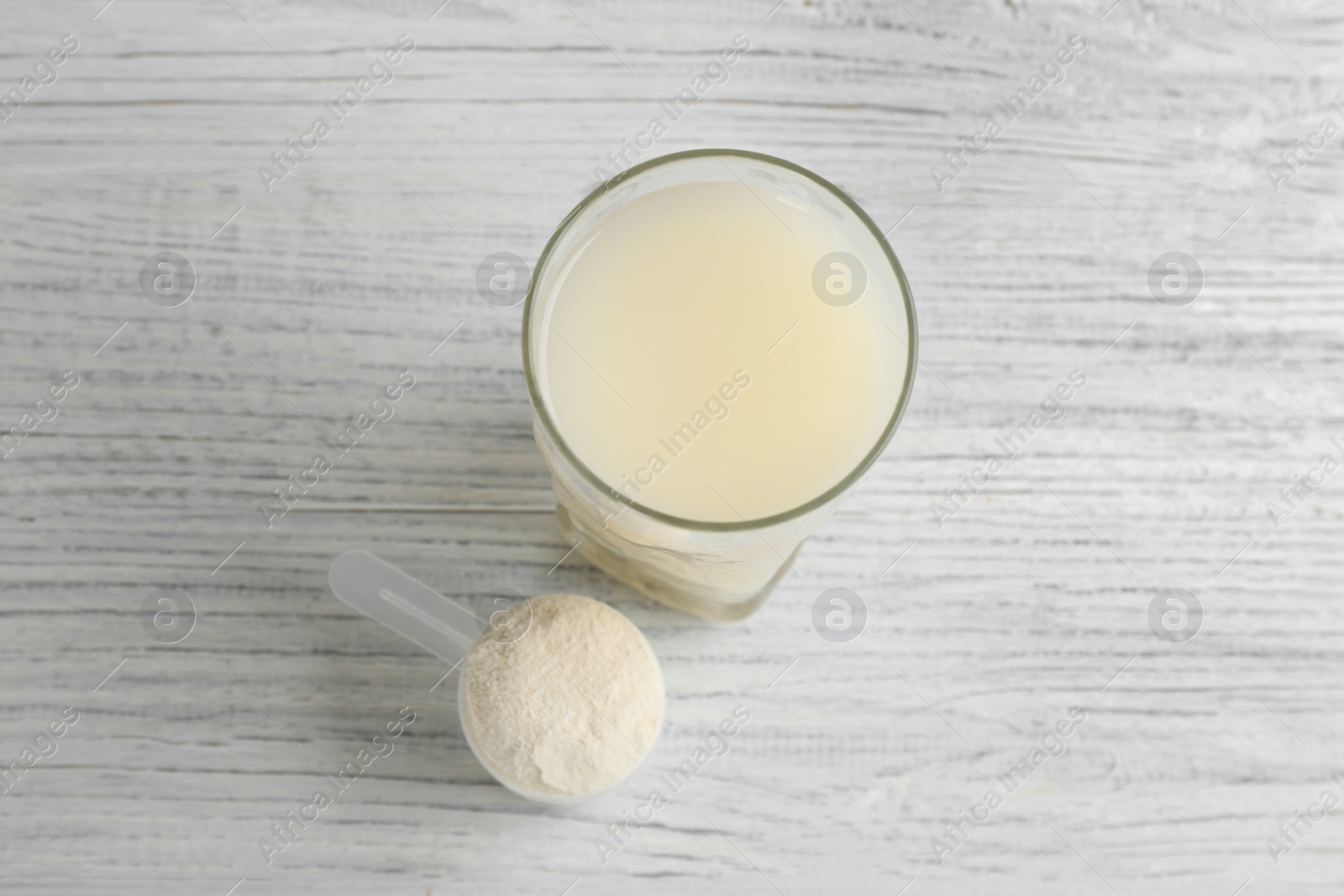 Photo of Protein shake and powder on white wooden table, above view