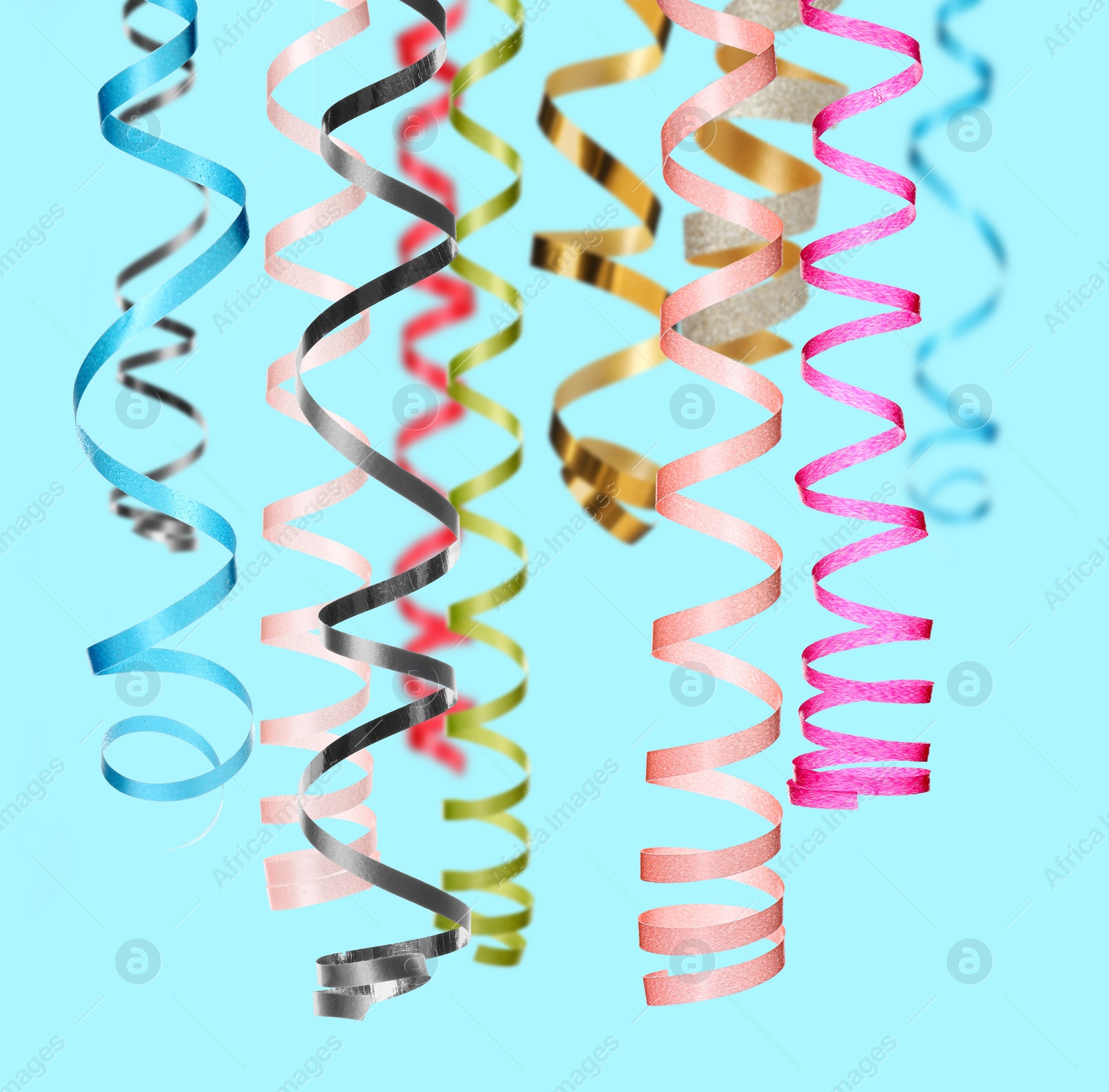 Image of Many serpentine streamers on light blue background. Party decor