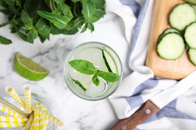 Photo of Glass of refreshing cucumber water and ingredients on white marble table, flat lay