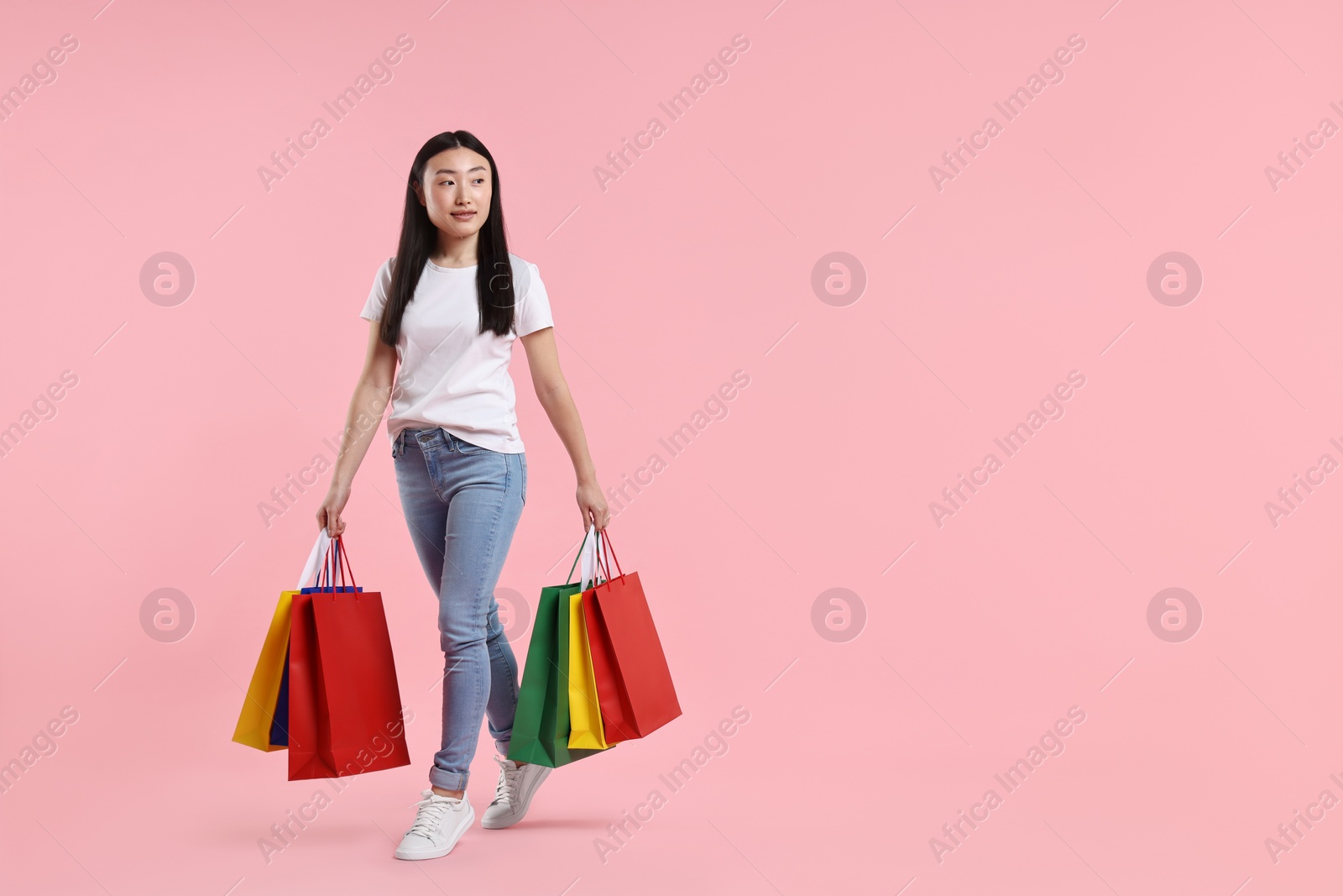 Photo of Beautiful woman with shopping bags on pink background. Space for text