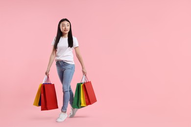 Photo of Beautiful woman with shopping bags on pink background. Space for text