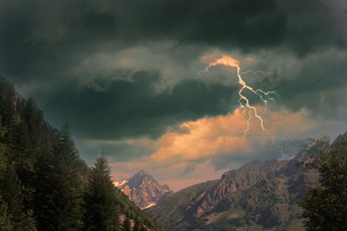 Image of Dark cloudy sky with lightnings over beautiful mountains. Thunderstorm