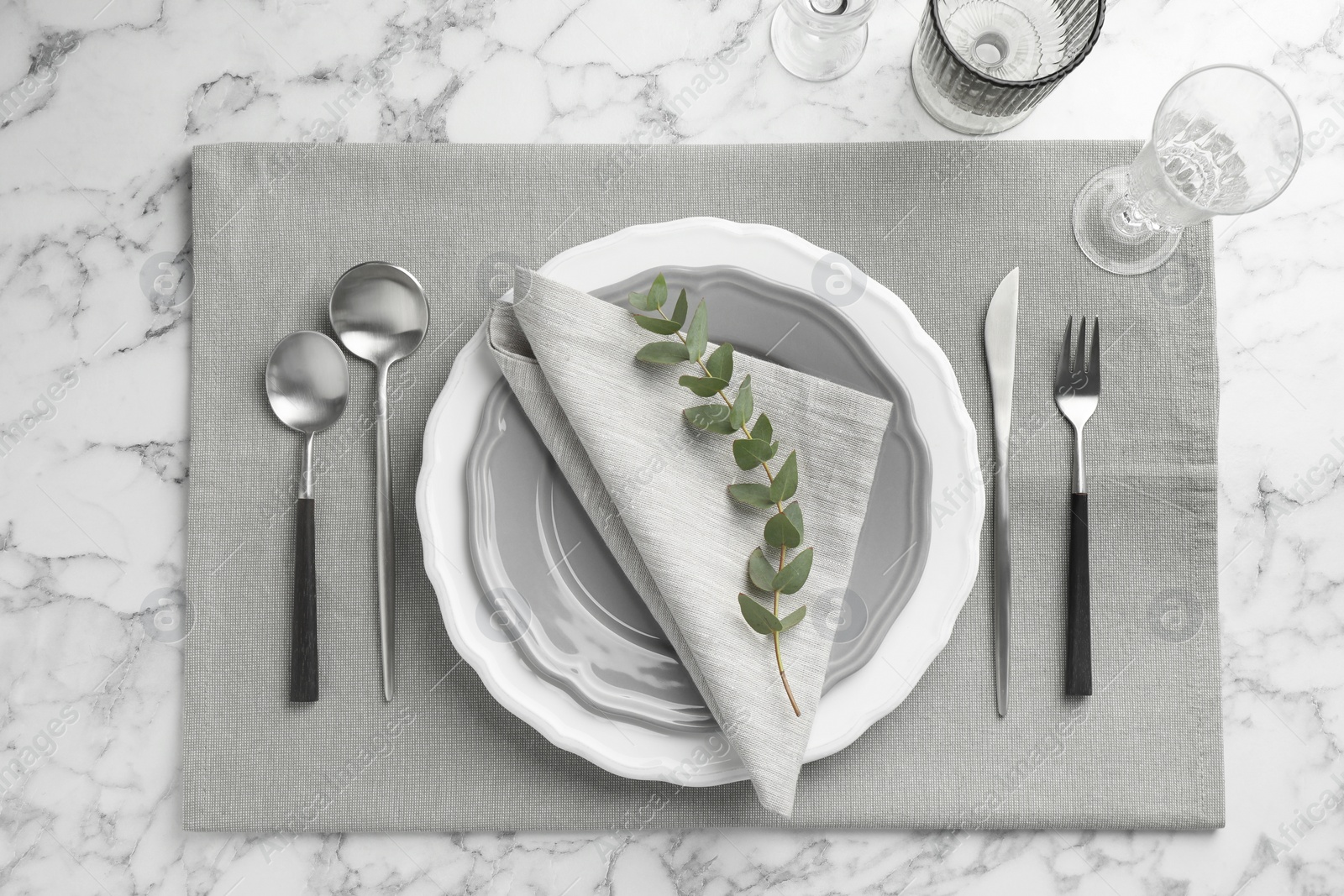 Photo of Stylish setting with cutlery, glasses and plates on white marble table, flat lay