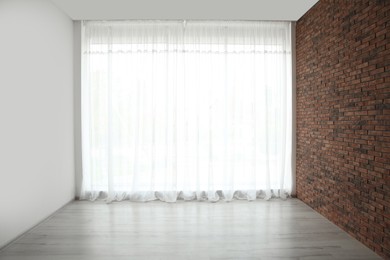 Photo of Empty room with brick wall and large window