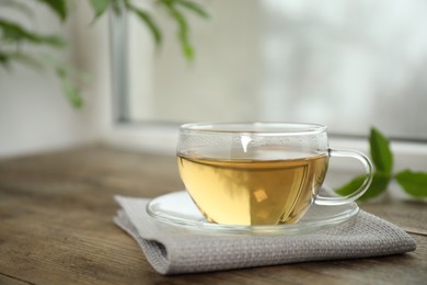 Tasty hot green tea in cup on wooden table