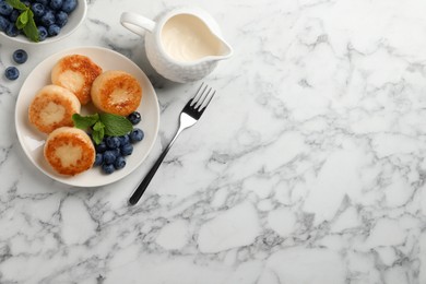 Delicious cottage cheese pancakes with blueberries, honey and mint on white marble table, flat lay. Space for text