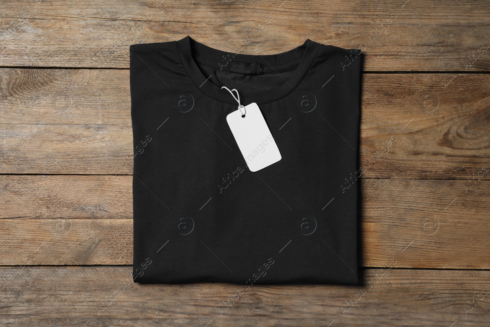 Photo of Stylish black T-shirt with label on wooden table, top view