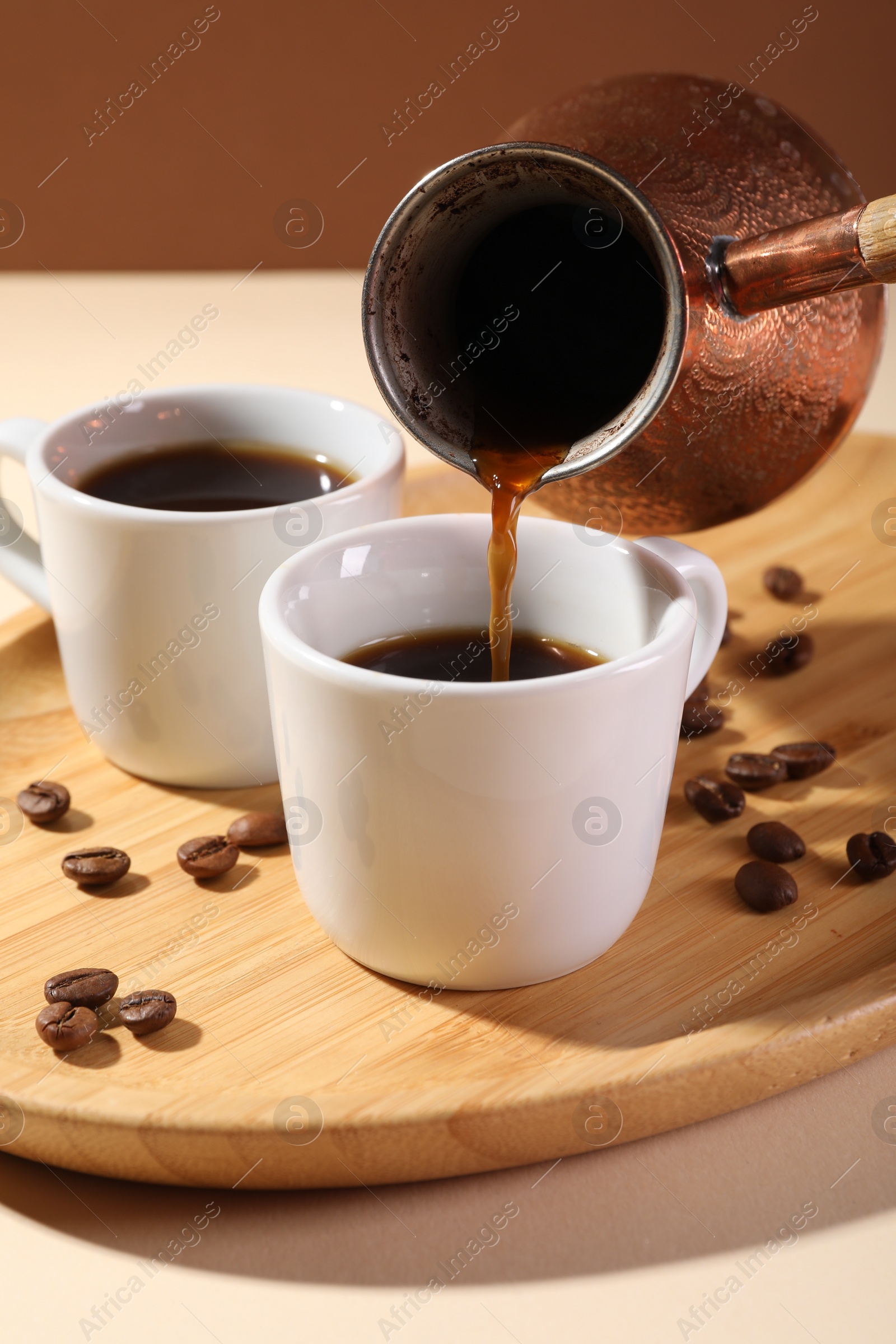Photo of Pouring aromatic coffee from cezve into cup at table, closeup