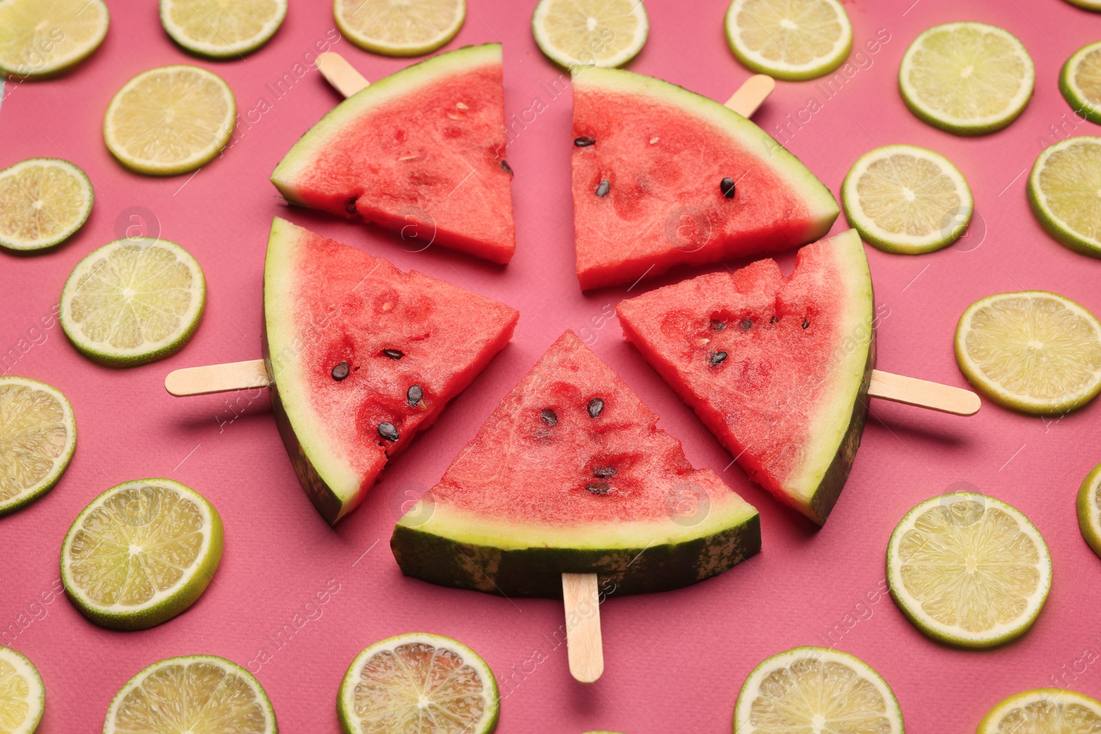 Photo of Tasty sliced watermelon and limes on red background, above view