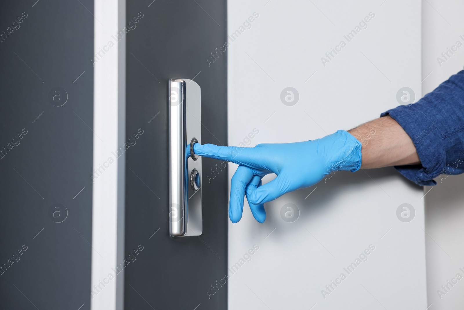 Photo of Man in glove pressing elevator call button, closeup. Protective measure