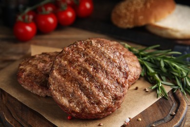 Photo of Tasty grilled hamburger patties with seasonings on wooden table, closeup