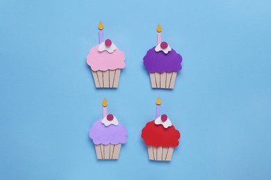 Photo of Birthday party. Paper cupcakes with candles on light blue background, flat lay