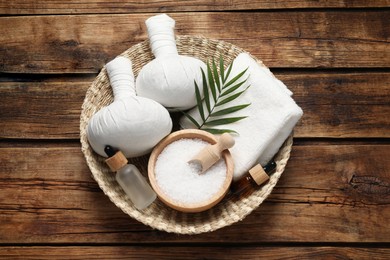 Photo of Composition with herbal massage bags and other spa products on wooden table, top view