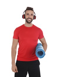 Handsome man with yoga mat and headphones on white background