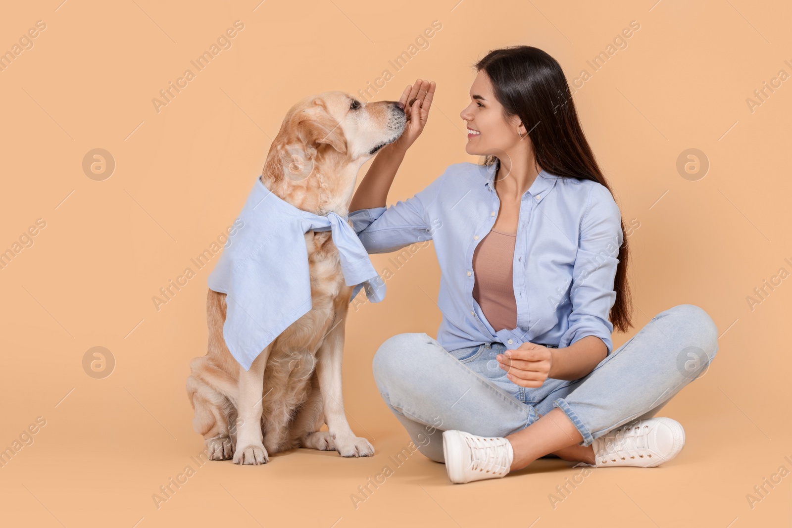 Photo of Happy woman with cute Labrador Retriever on beige background