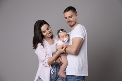 Photo of Happy family. Couple with their cute baby on grey background